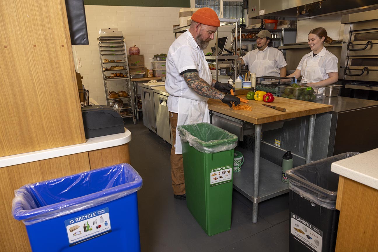 Three bins and three kitchen staff in commercial kitchen