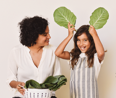 Girl and mother with bowl of salad greens.