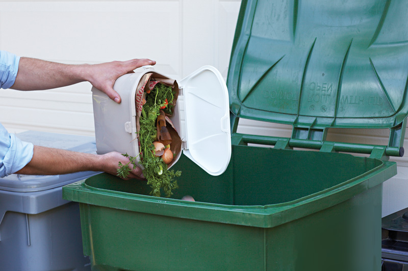 dumping a compost pail into the curbside green bin