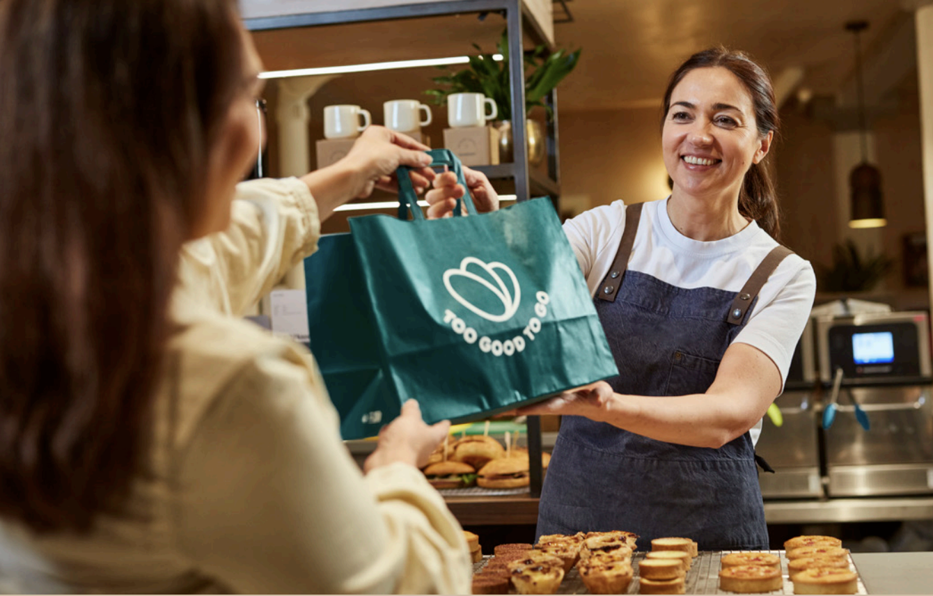 woman handing a bag over a counter at a cafe