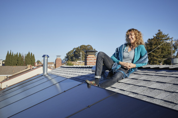 Woman next to solar panels on her roof