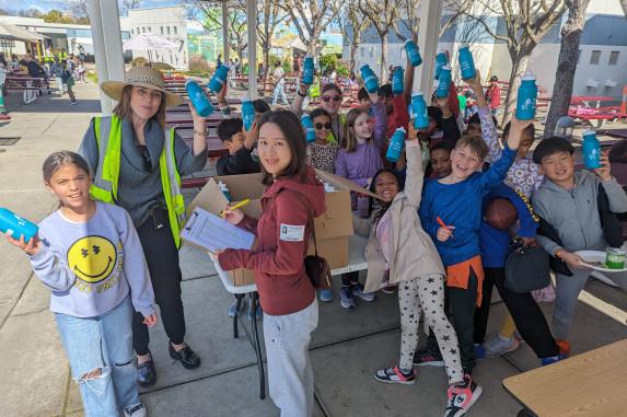 more than 15 students and two adults celebrating with reusable water bottles in hand