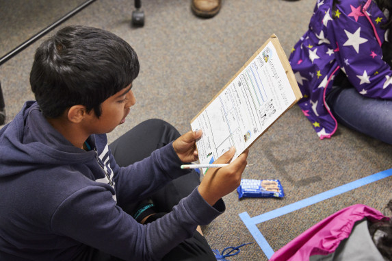 Student looking down at worksheet on clipper with pencil in hand