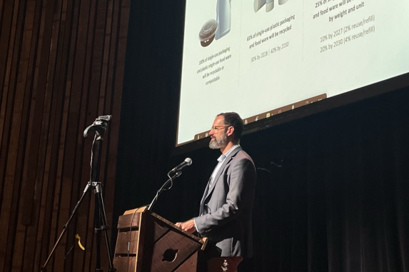 Man standing at podium with presentation in background