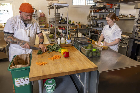 Man prepping on side of commercial kitchen area and woman prepping on other