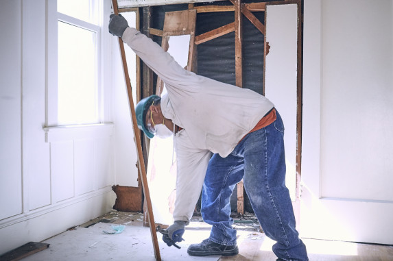 Man with construction tool and wooden plank in hand