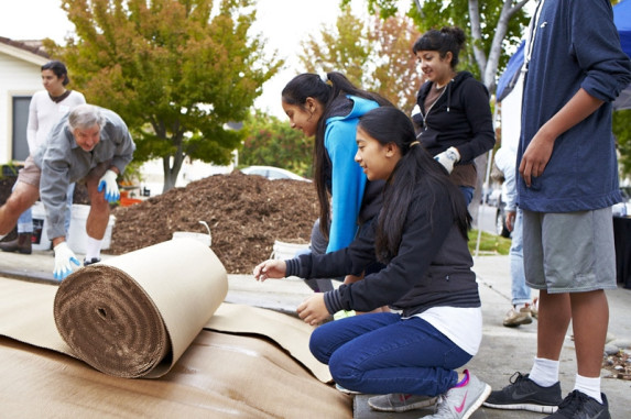 Group of residents rolling roll of paper on ground